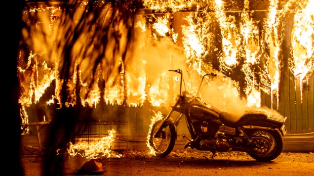 A structure and a motorcycle burn at an RV park during the Woolsey Fire in Malibu